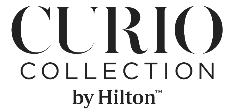 The image shows the logo for "Curio Collection by Hilton," a hotel brand known for its unique and upscale accommodations.