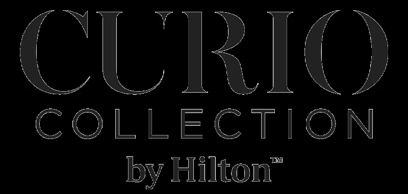 The image shows the logo for "Curio Collection by Hilton," a hotel brand known for its unique and upscale accommodations. logo on footer section.