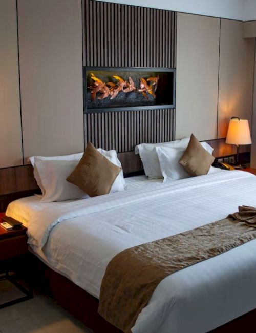 A cozy hotel room with a large bed, two side tables with lamps, a small wall art piece above the bed, and curtains to the right.