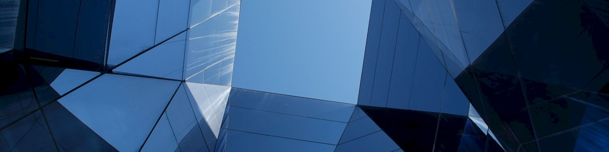 The image shows a view of modern, reflective skyscrapers with a square patch of sky visible at the center, creating a geometric pattern.