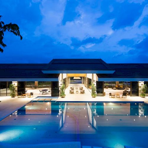 A modern building with a large illuminated pool in the foreground and evening sky in the background.