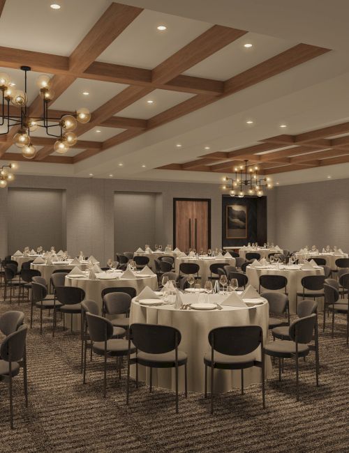 The image shows a banquet hall set up with round tables, chairs, chandeliers, and neutral decor, ready for an event or gathering.