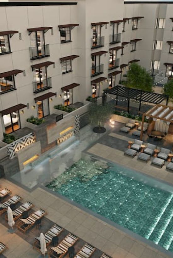 The image shows an outdoor courtyard with a pool, lounge chairs, and seating areas surrounded by a multi-story building.