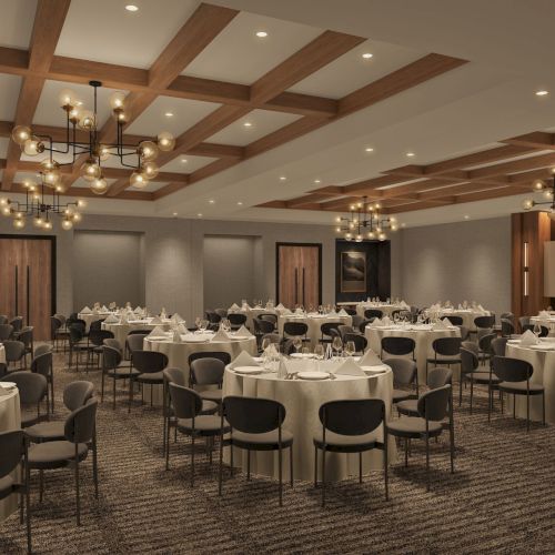 A modern banquet hall with round tables set for dining, elegant chandeliers, wooden paneling, and neutral decor.