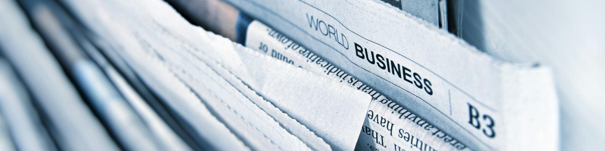 Close-up of blue binders in an office filing cabinet with tabs labeled &ldquo;WORLD BUSINESS.&rdquo;