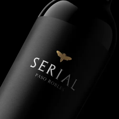 A dark wine bottle with the label “SERIAL” and “PASO ROBLES,” featuring a small golden butterfly emblem.