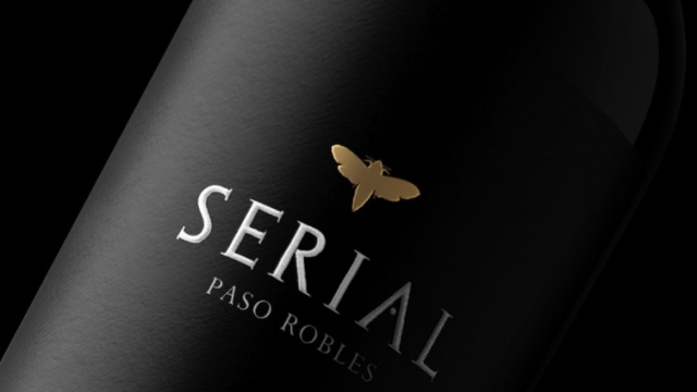 A dark wine bottle with the label &ldquo;SERIAL&rdquo; and &ldquo;PASO ROBLES,&rdquo; featuring a small golden butterfly emblem.