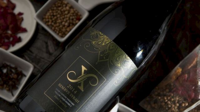 A wine bottle lies amid assorted spice bowls&mdash;peppercorns, dried chilies, and star anise.